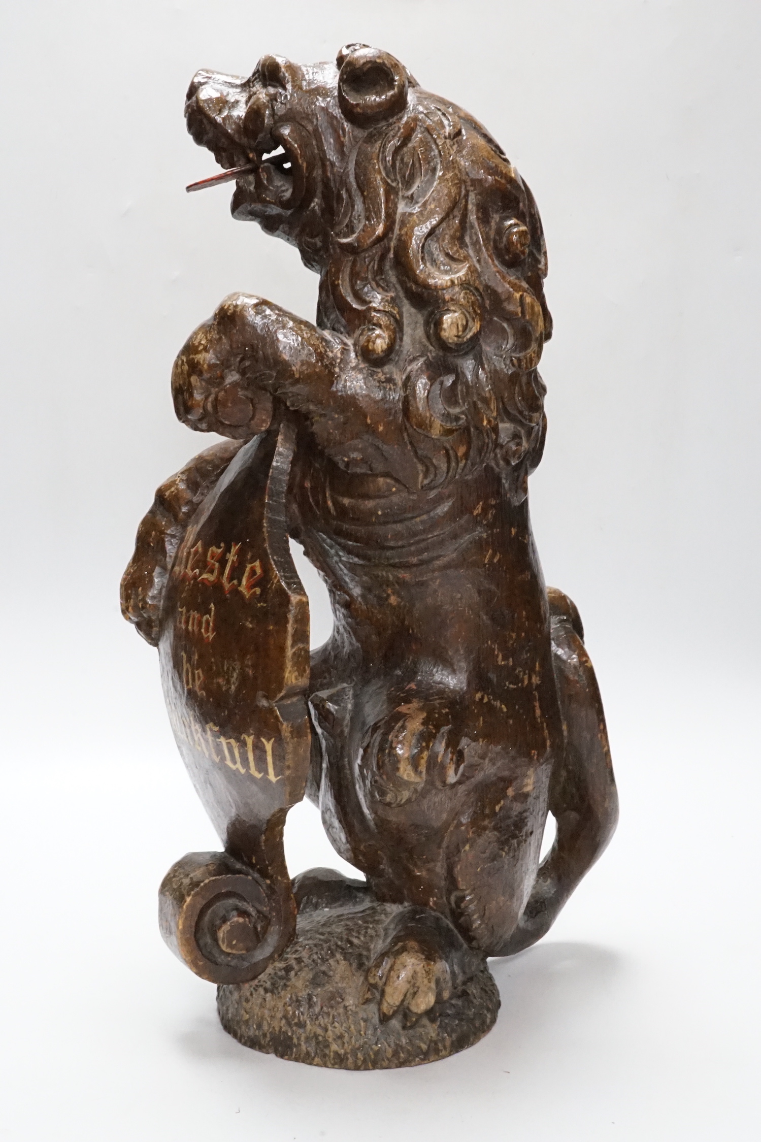 A carved oak lion holding a shield with inscription, possibly 17th/18th century with Victorian inscription Reste and be Thankfall, 48cm high